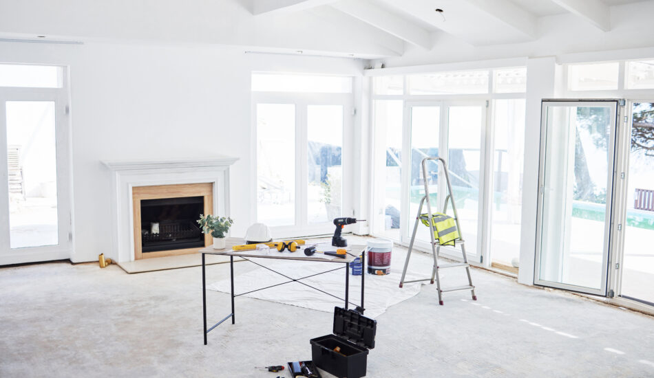 Shot of building plans and equipment on a table in an empty living room during the day.