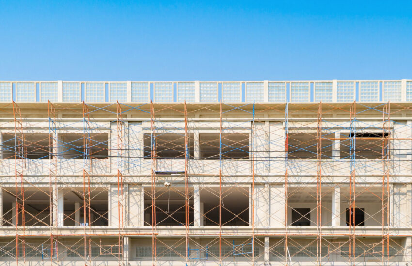 Scaffolding of house building. Lattice mast, cables or poles in busy industrial under construction site with cranes. Steel or metal structure. Development stucture architecture. Real estate.